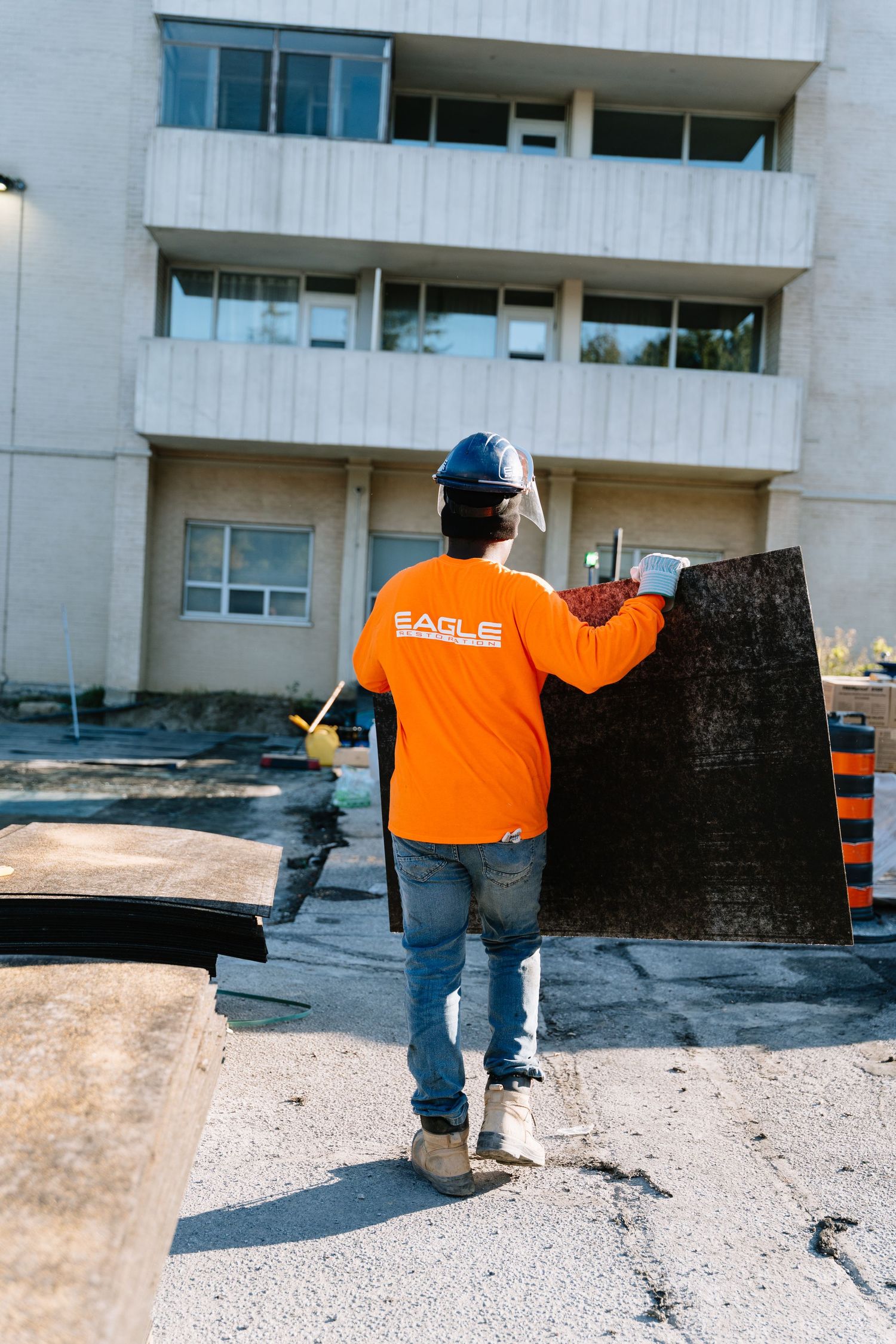 Construction workers in orange safety vests inspect and measure a concrete surface at a building site.