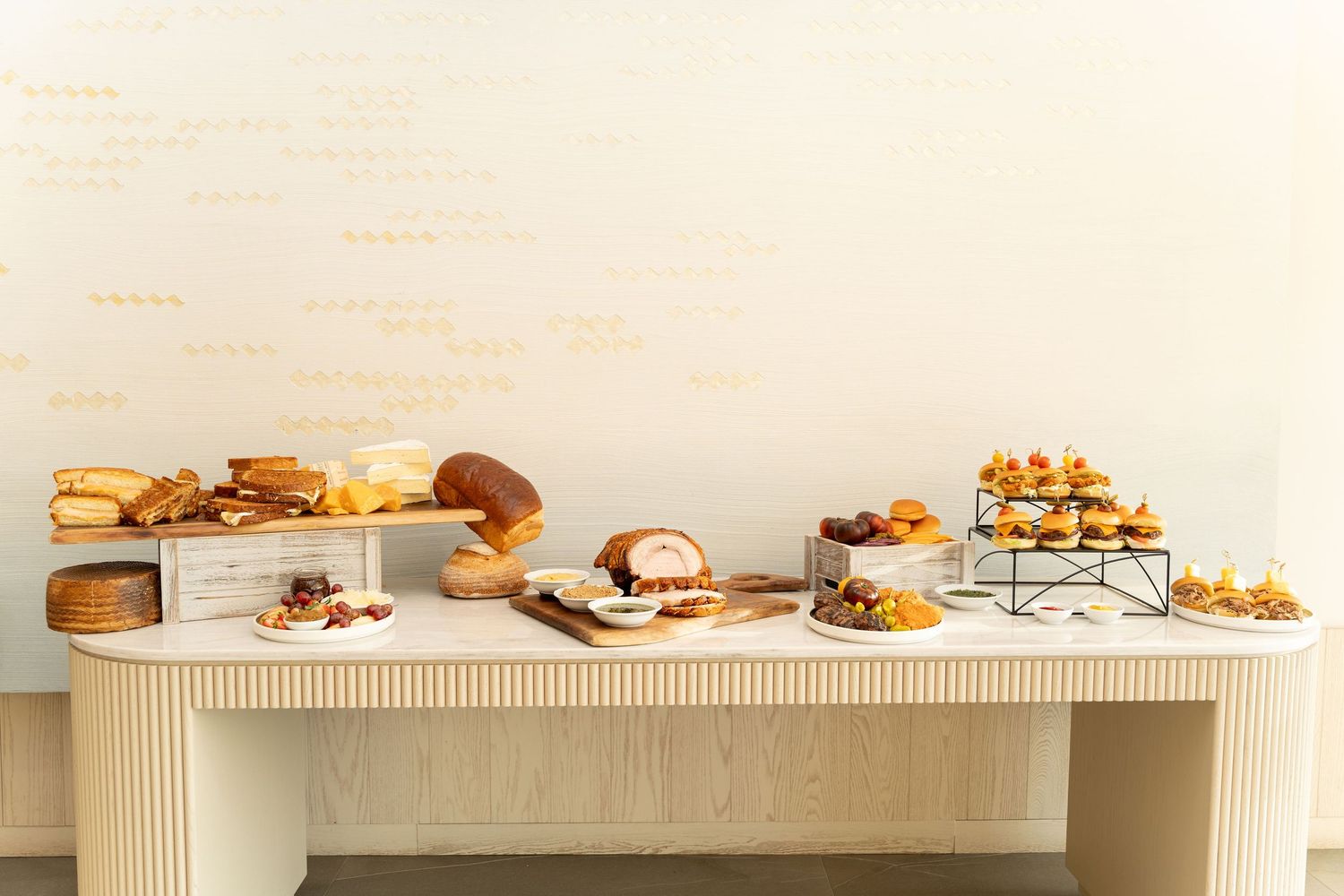 White modern buffet table display with assorted pastries and baked goods arranged neatly.