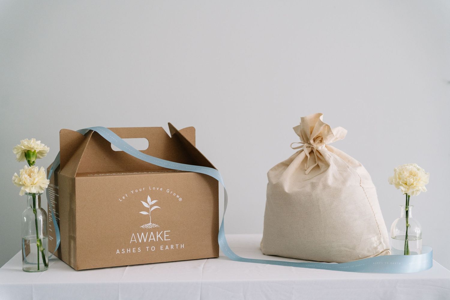 Elegant brown cardboard gift boxes with floral decorations and white packaging displayed in a minimalist setting.
