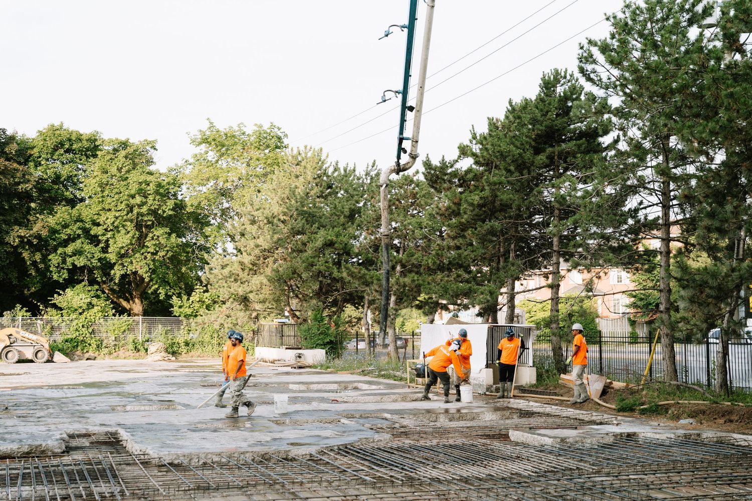 Group in bright orange safety vests walking along a path with trees and utility poles in the background.
