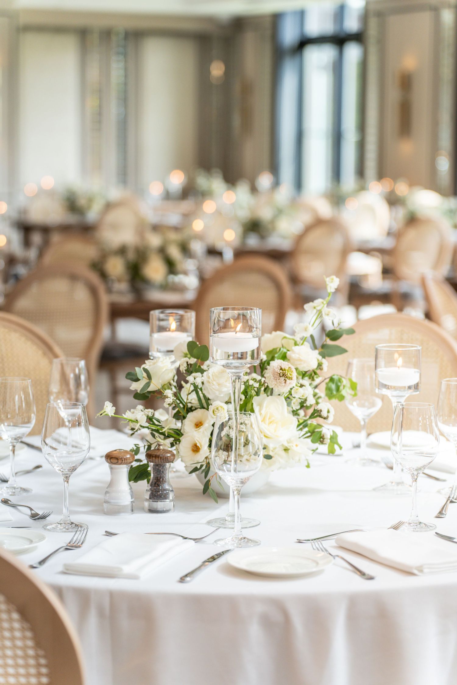 Elegant wedding reception tables set with crisp white linens, delicate floral centerpieces and crystal glassware.