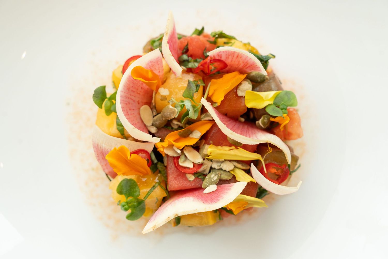 Vibrant citrus and prosciutto salad with fresh herbs arranged in a circular pattern.