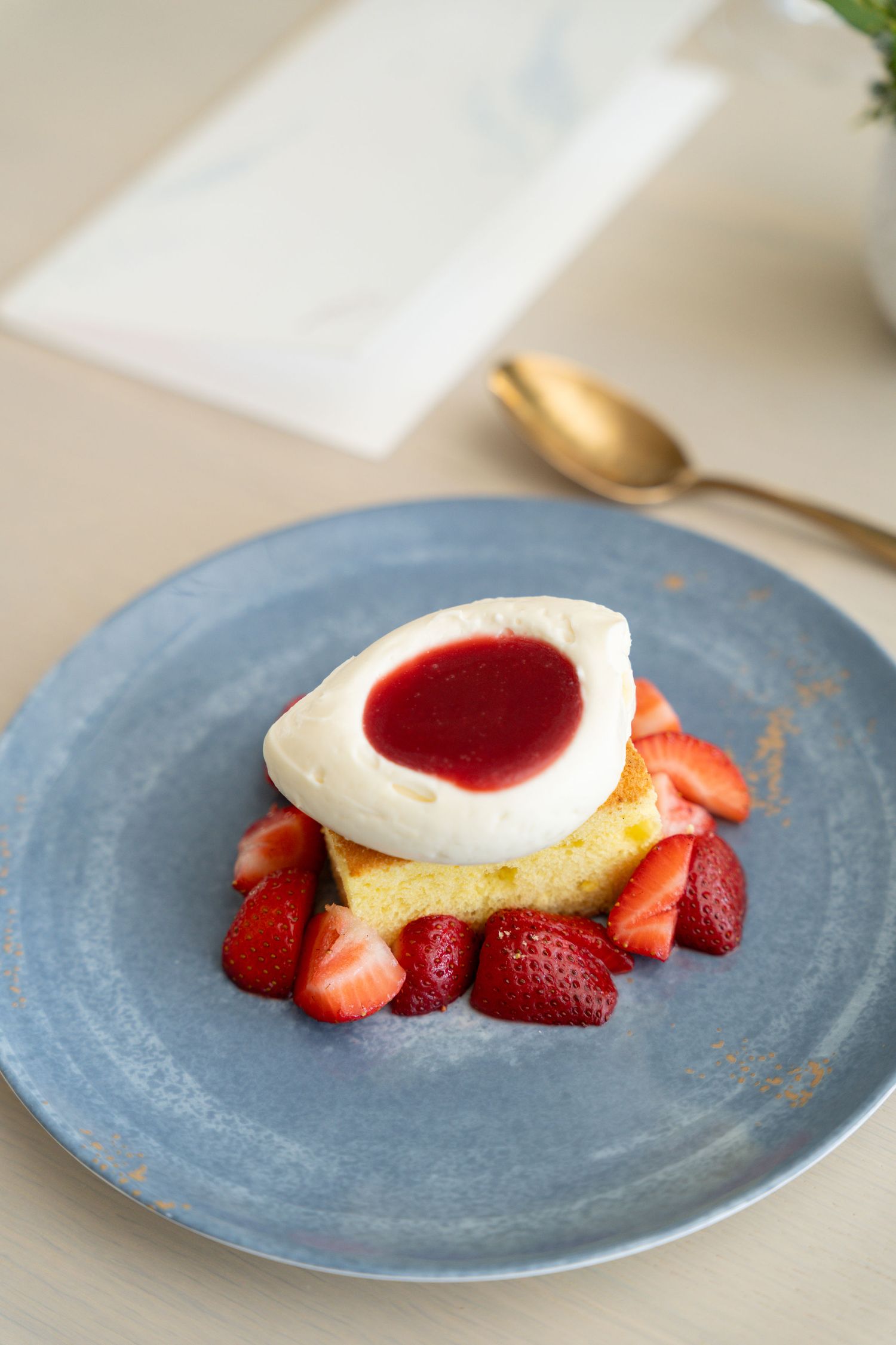 Deconstructed dessert with fresh strawberries and white cream served on textured blue plates.