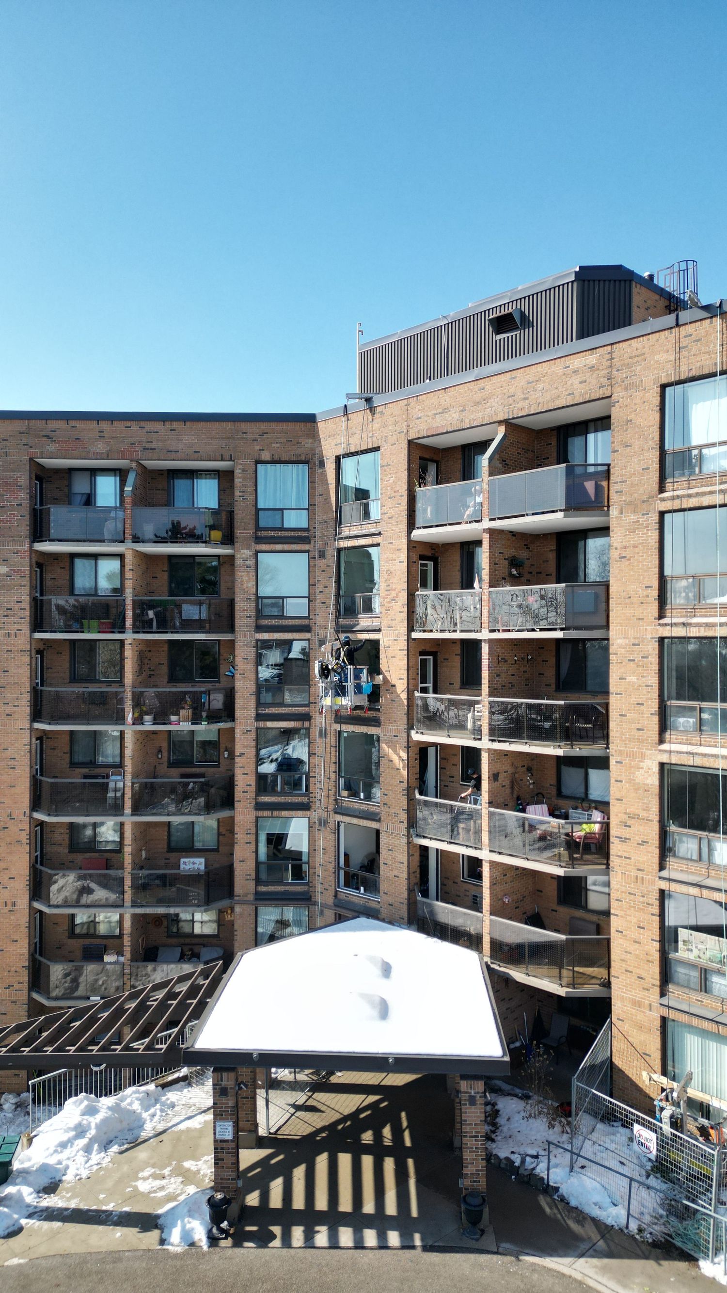 Modern brick apartment complex with multiple balconies and large windows covered in snow.