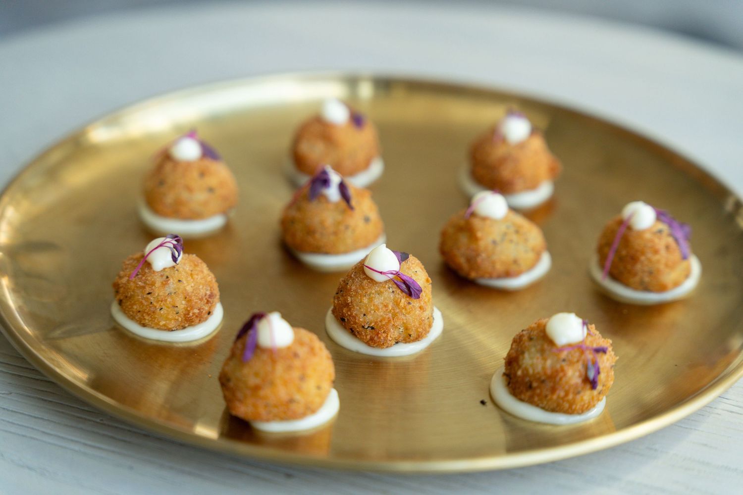 Golden whoopie pies with cream filling arranged on a shiny metallic serving platter.