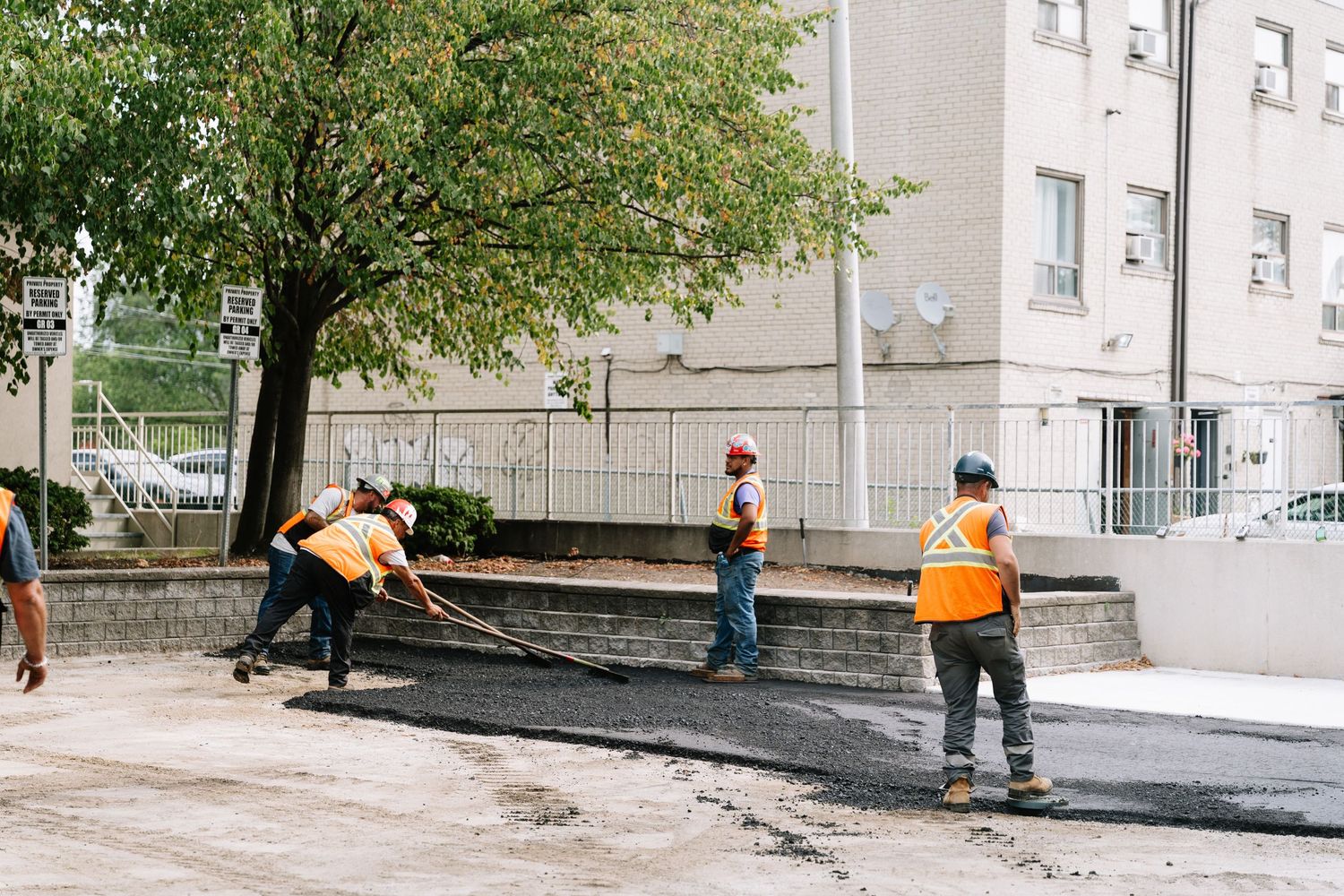Heavy machinery and workers preparing a construction site outside an apartment complex.