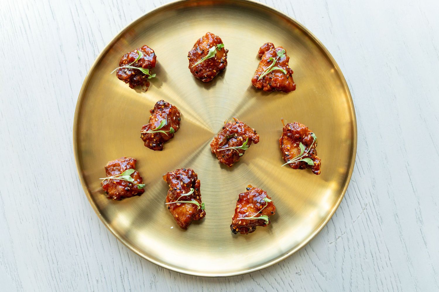 Golden serving platter displaying artfully arranged bruschetta bites on a white surface.