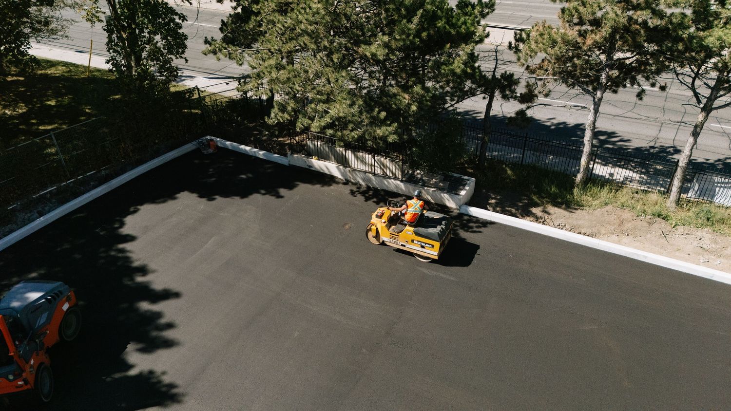 Aerial view of a yellow taxi cab driving on an asphalt road near trees and shadows.