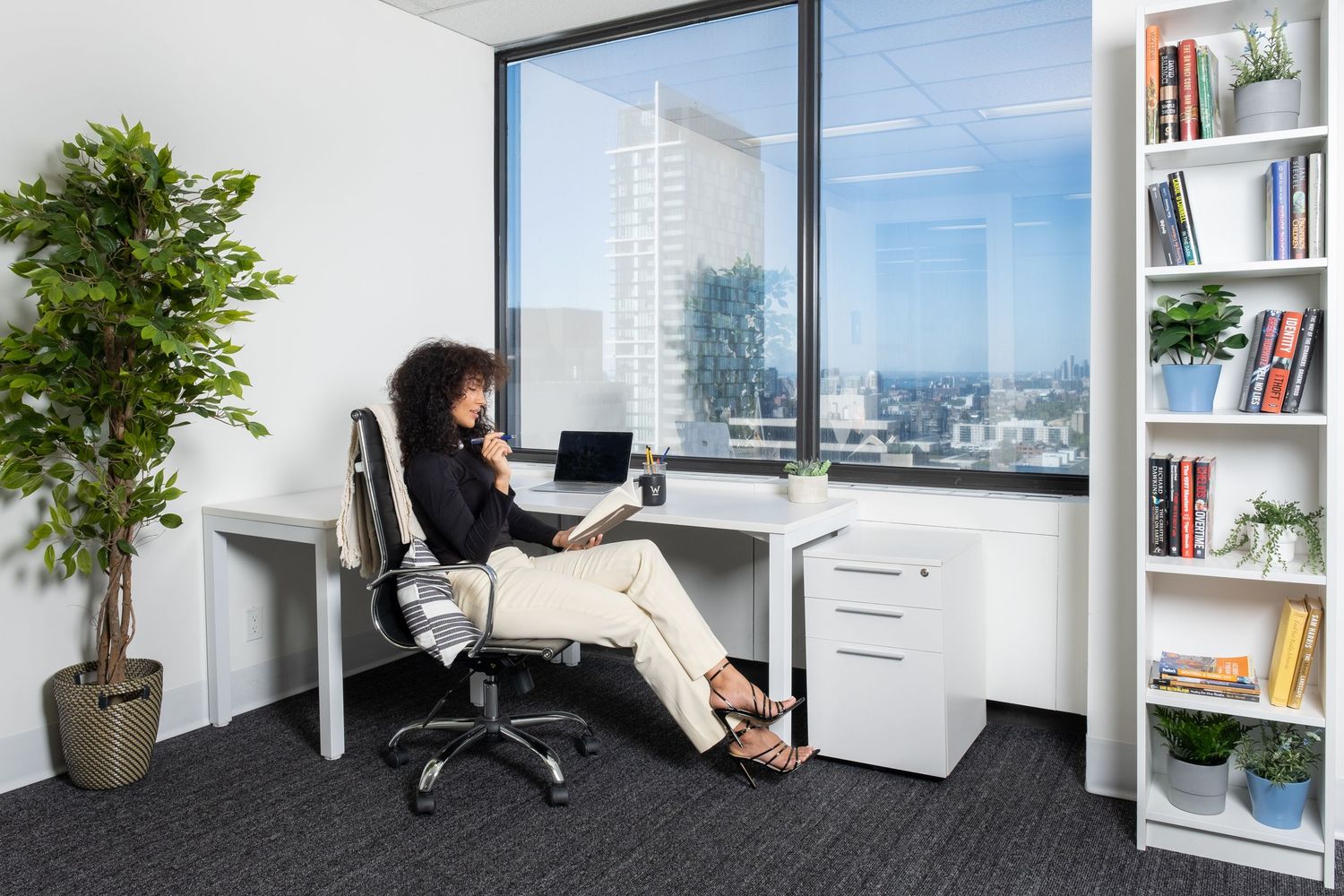 Modern white office space with natural light, plants, and ergonomic furniture creates a bright professional environment.