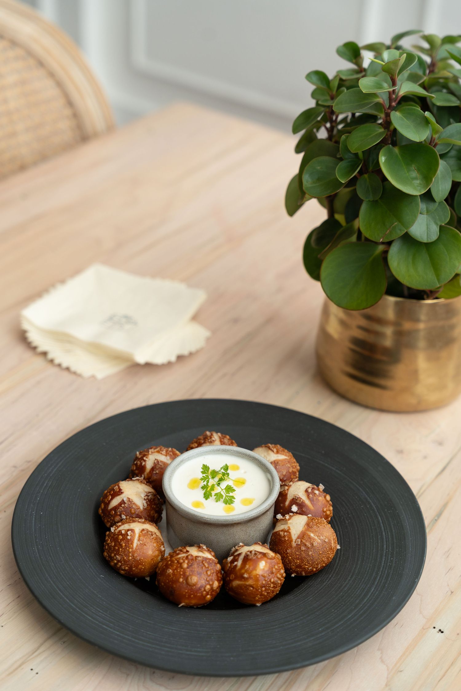 Breaded mushrooms arranged in circle around white dipping sauce on black plate.
