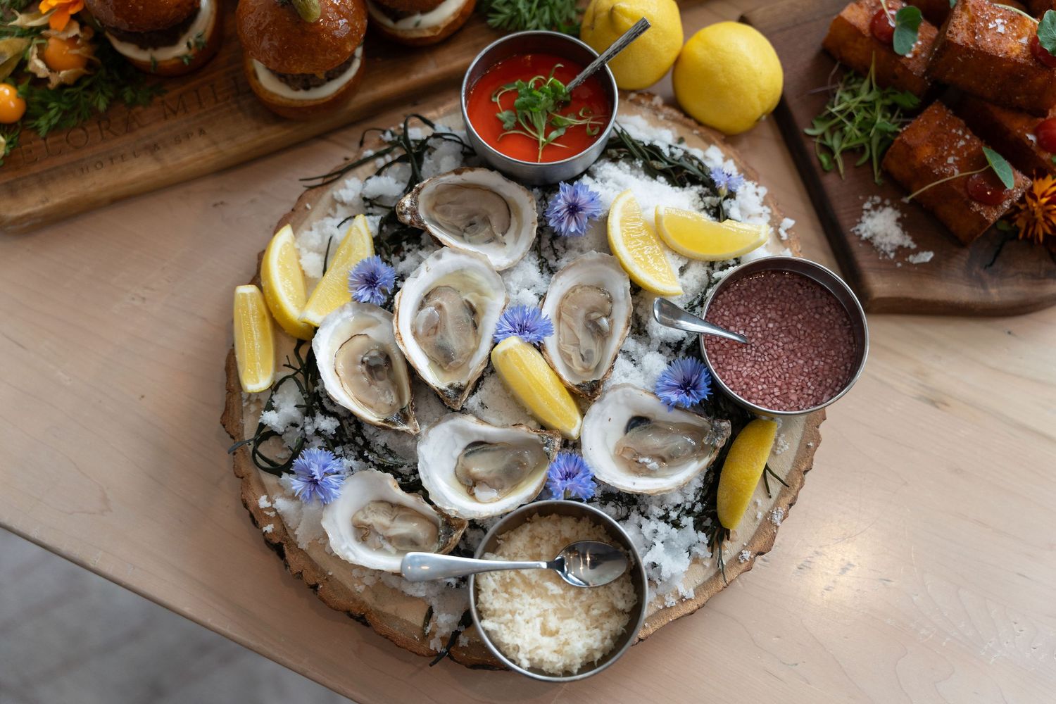 Fresh oysters on ice served with lemon wedges and sauce in a rustic restaurant setting.