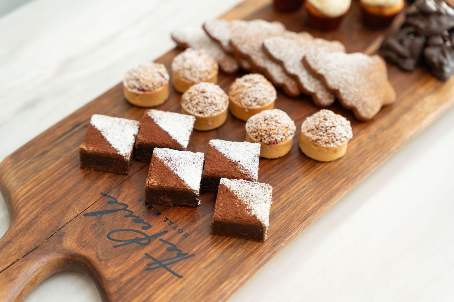 Artisanal chocolate truffles and macarons displayed on rustic wooden serving board.