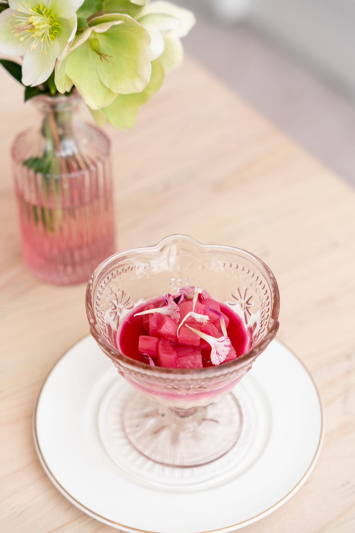 Pink glass dessert bowls with delicate floral patterns display bright red jello on white plates with a soft floral accent.