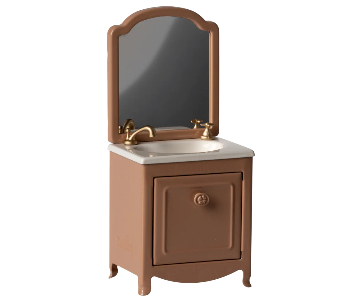 Vintage style brown wooden vanity with curved mirror and brass fixtures mounted above single cabinet storage base.