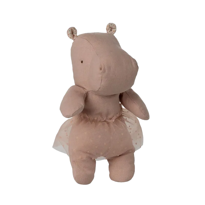 Soft plush hippo toy wearing a delicate tulle dress in pale dusty pink color stands against white background.