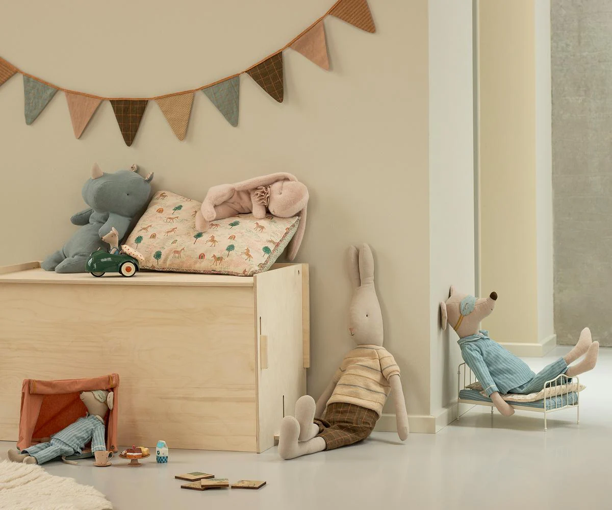 Cozy nursery corner with bunting flags, plush toys, and soft pastel decor in muted tones.