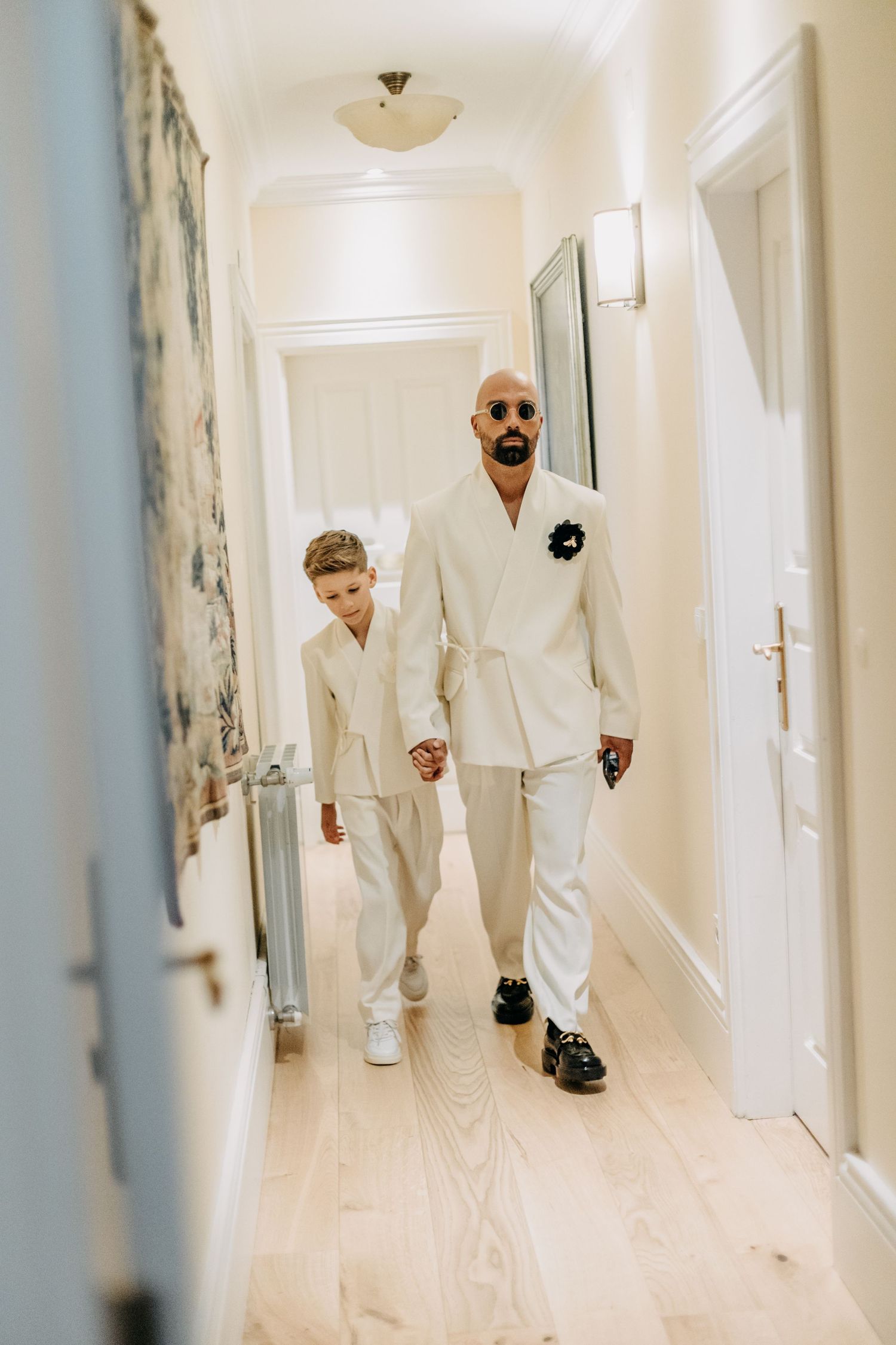 Four sequential photos show a person in white clothing walking down a bright hallway with pale blue walls.