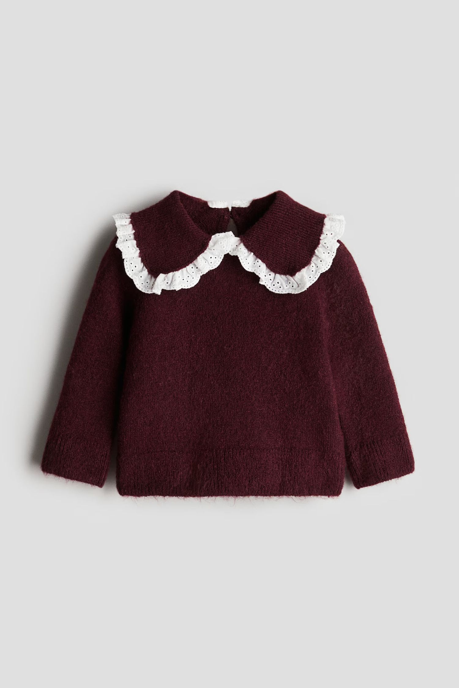 Burgundy knit baby sweater with white lace peter pan collar on light gray background.