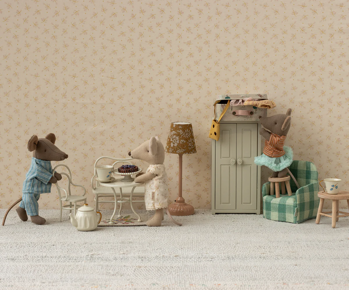 A collection of miniature vintage-style toys and furniture arranged in a row against a neutral beige background.