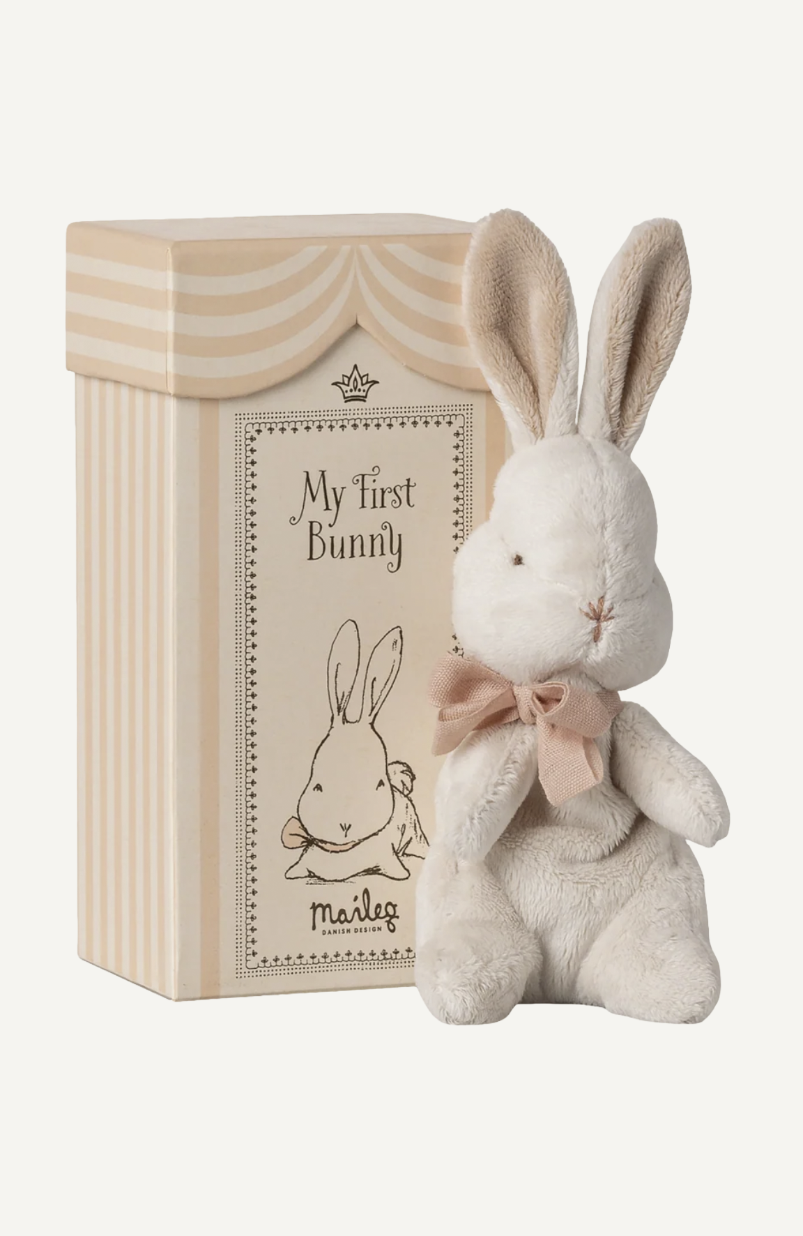 Maileg My First Bunny soft toy in cream with pink bow tie, displayed beside its decorative striped gift box.
