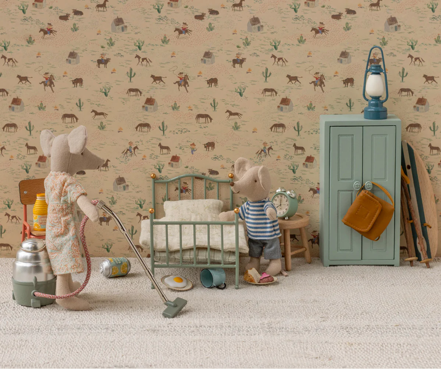 Cozy vintage children's room with stuffed mice toys, metal bed, blue wardrobe and lantern against floral wallpaper.