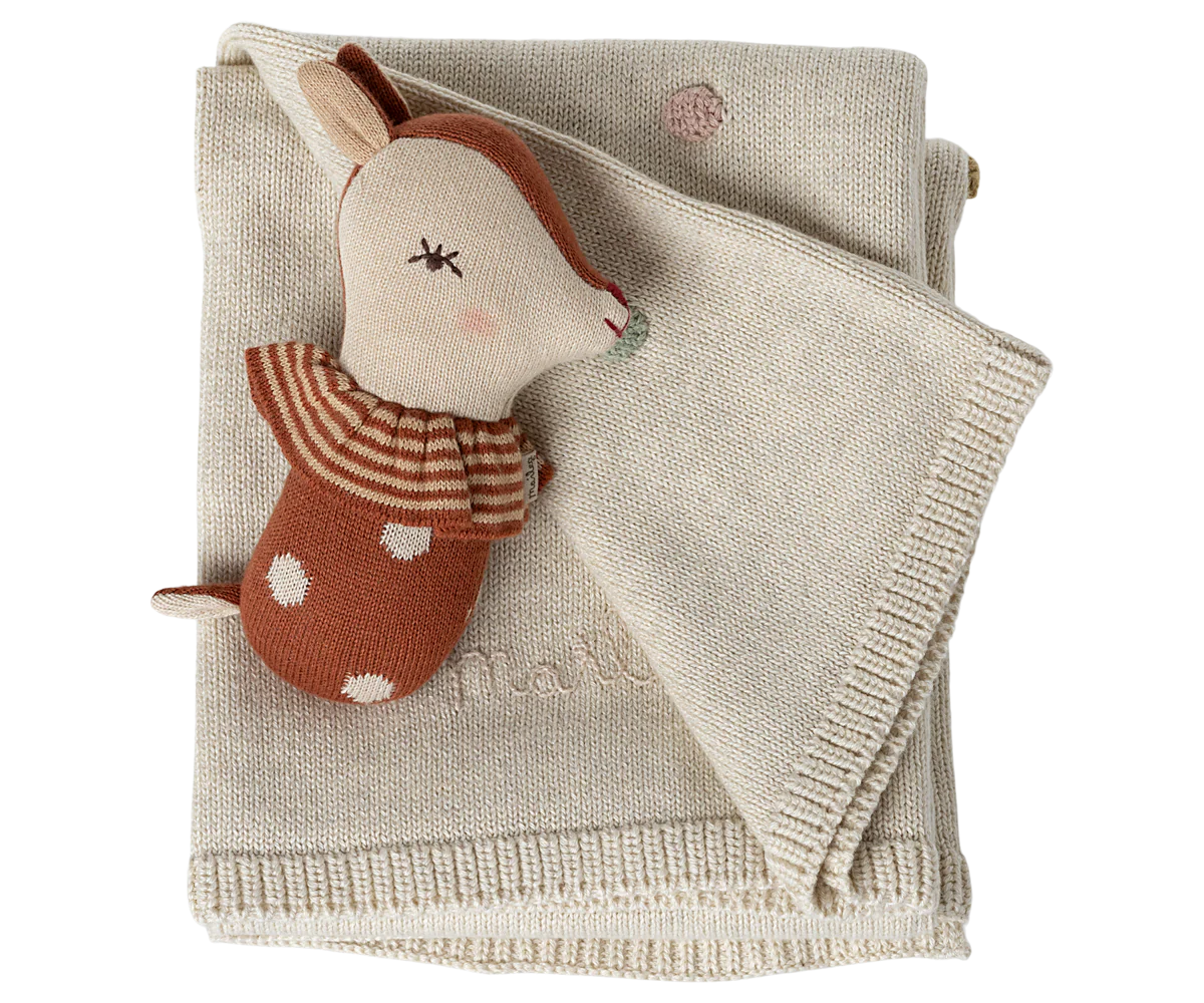 A set of beige linen placemats with decorative stitching and embroidered brown penguin designs along the edges.