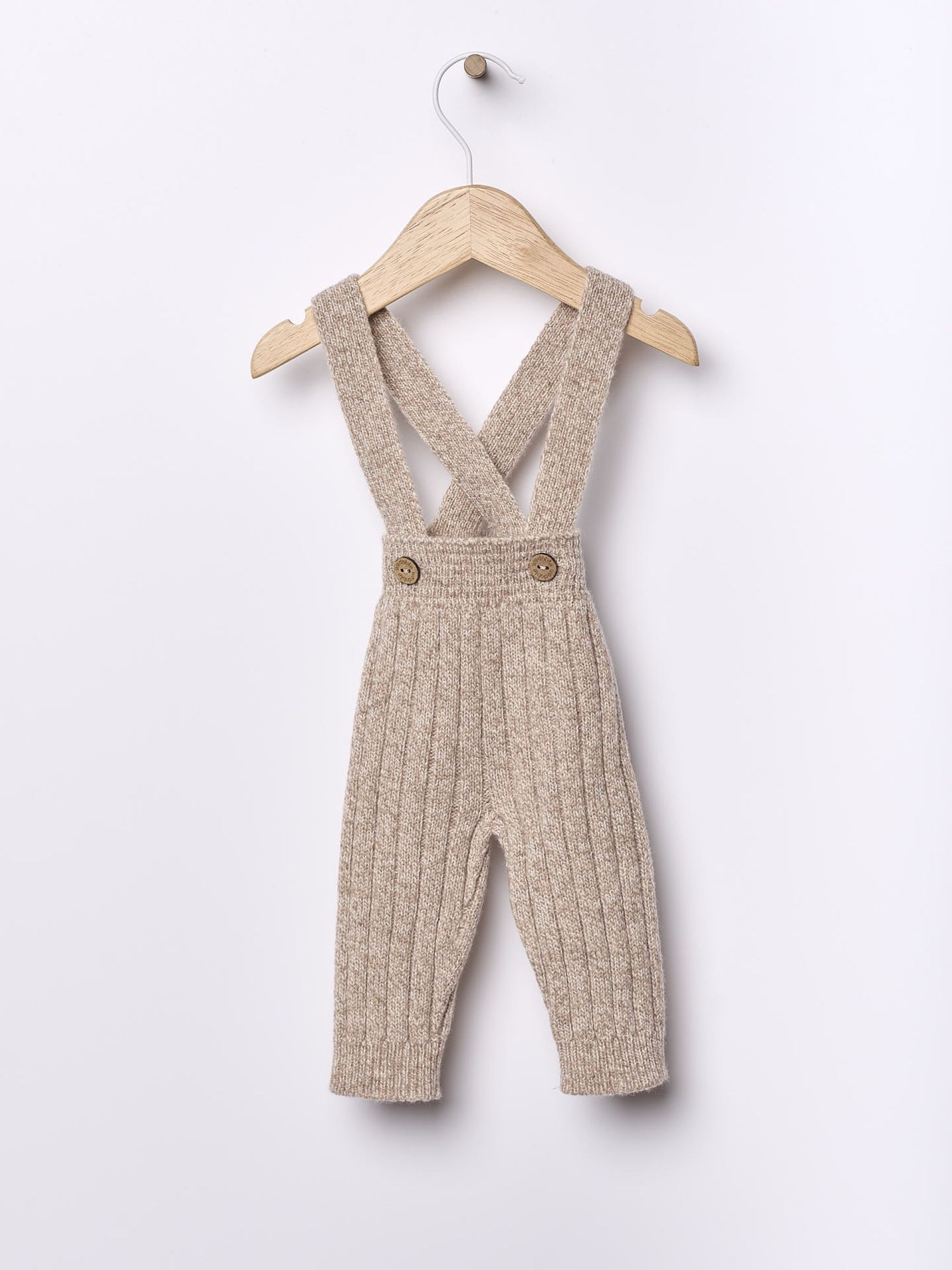 Adorable handmade beige knitted baby overalls with decorative buttons displayed on a white background.