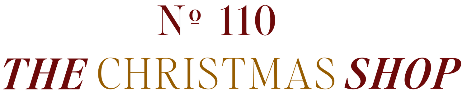 A white Christmas shop storefront sign displaying number 110 and gold lettering.