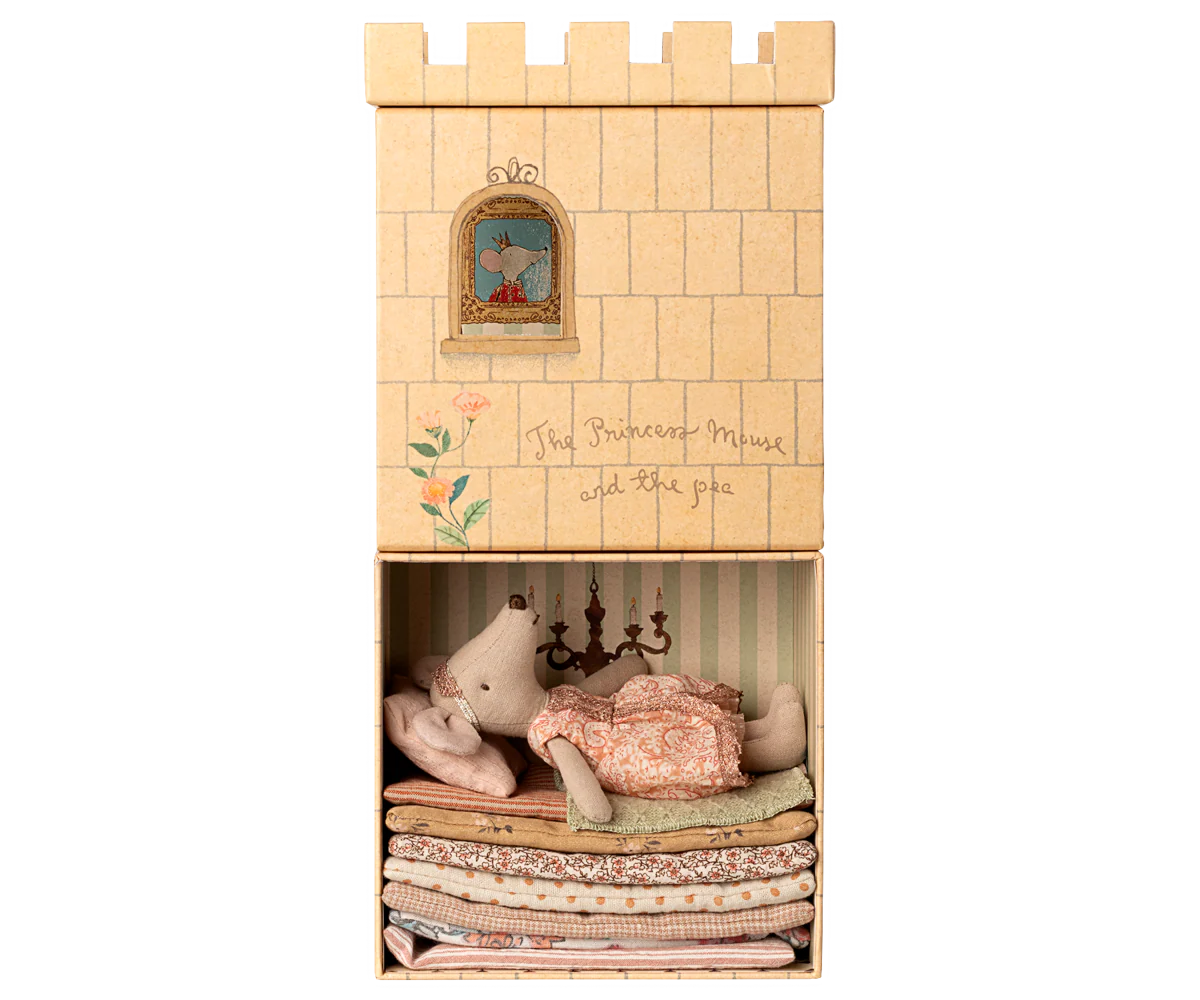 Fairy tale inspired photo of a small child sleeping on a stack of mattresses with a castle wall backdrop.
