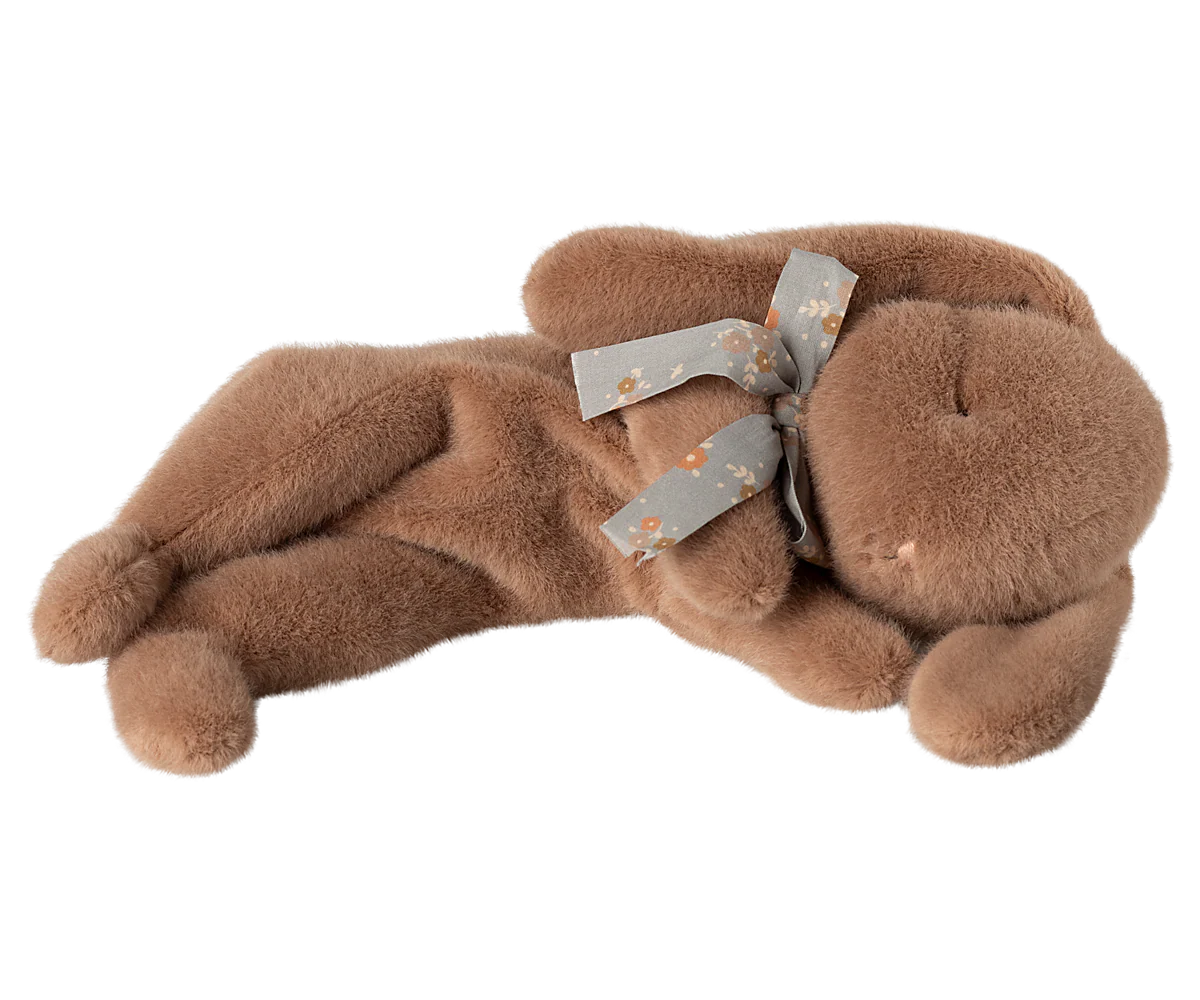 A brown plush stuffed dog toy with gray ribbons lying on its side against a white background.