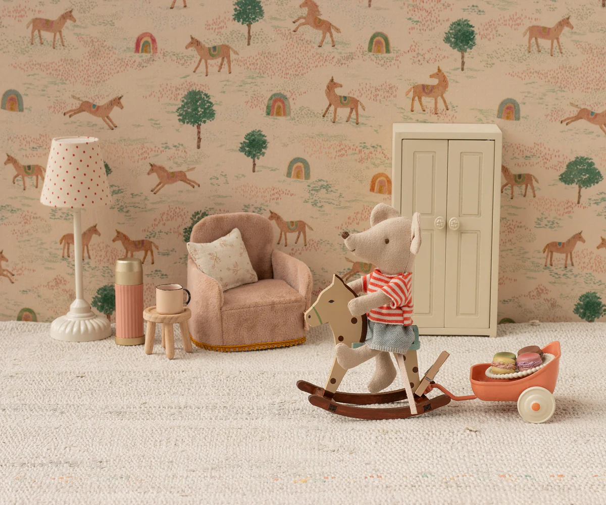 Vintage wooden toys and decor arranged against rustic wallpaper with horse and tree motifs.