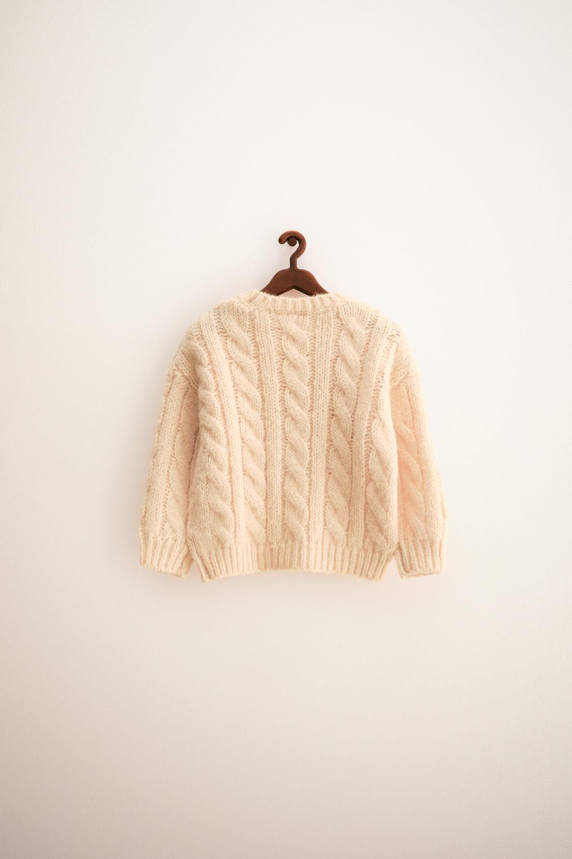 A cream-colored cable knit baby sweater shown from different angles against a white background.