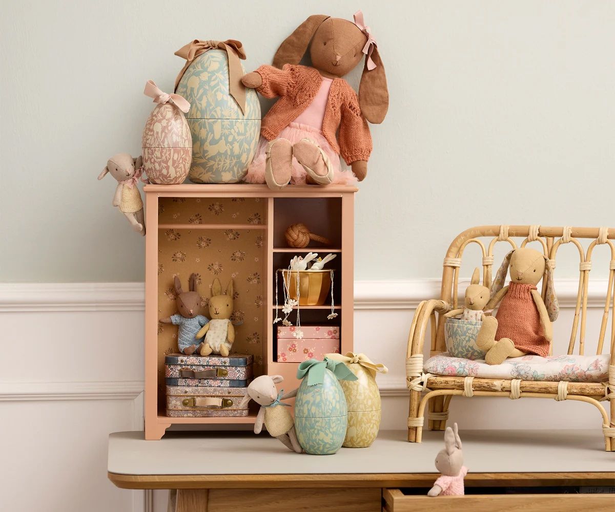 Rustic wooden shelving displays soft plush toys and decorative vases in a minimalist nursery setting.