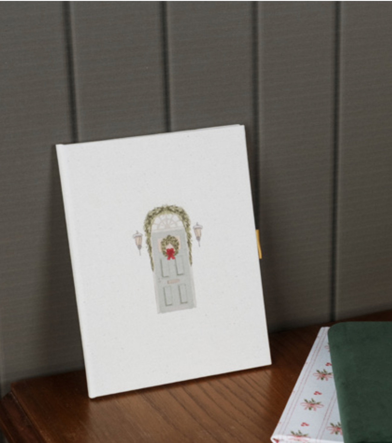 A simple white canvas art piece displaying a small watercolor illustration of a floral archway on a wooden table.