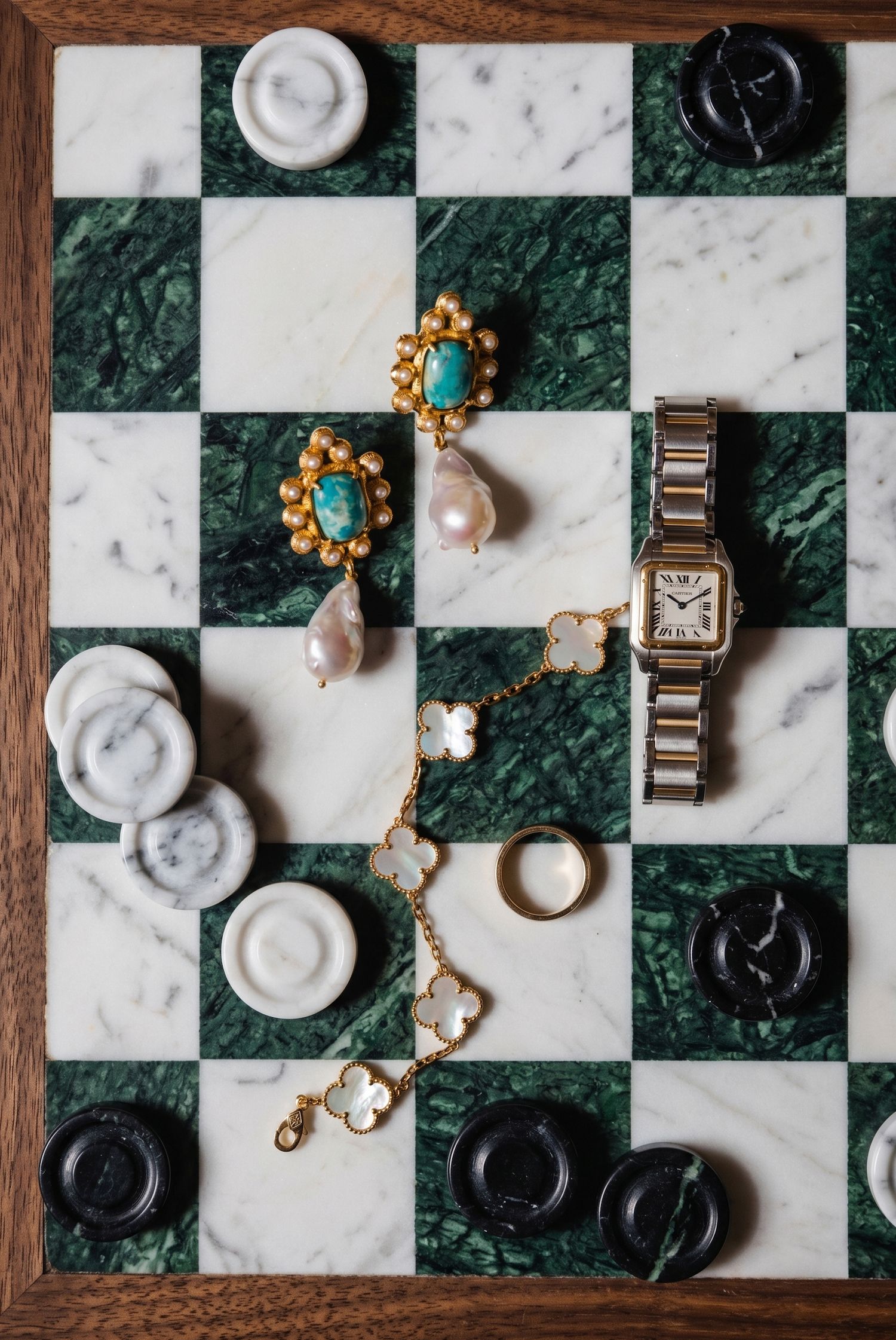 Marble checkerboard with gold Cartier watch, Van Cleef bracelet, turquoise pearl earrings, and checker pieces.