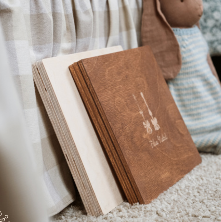 Aesthetic photo of brown and white hardcover books stacked on a carpeted floor beside white fabric.