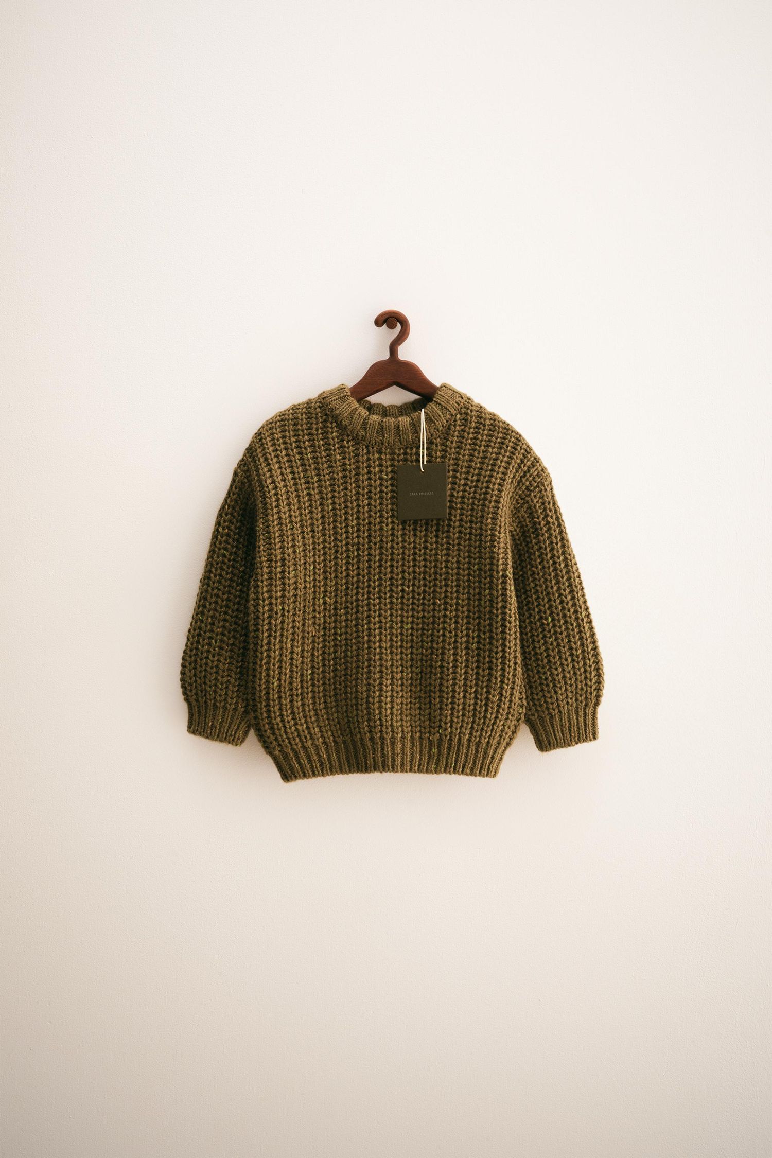 A knitted olive green cropped sweater with ribbed texture shown from different angles against a white background.