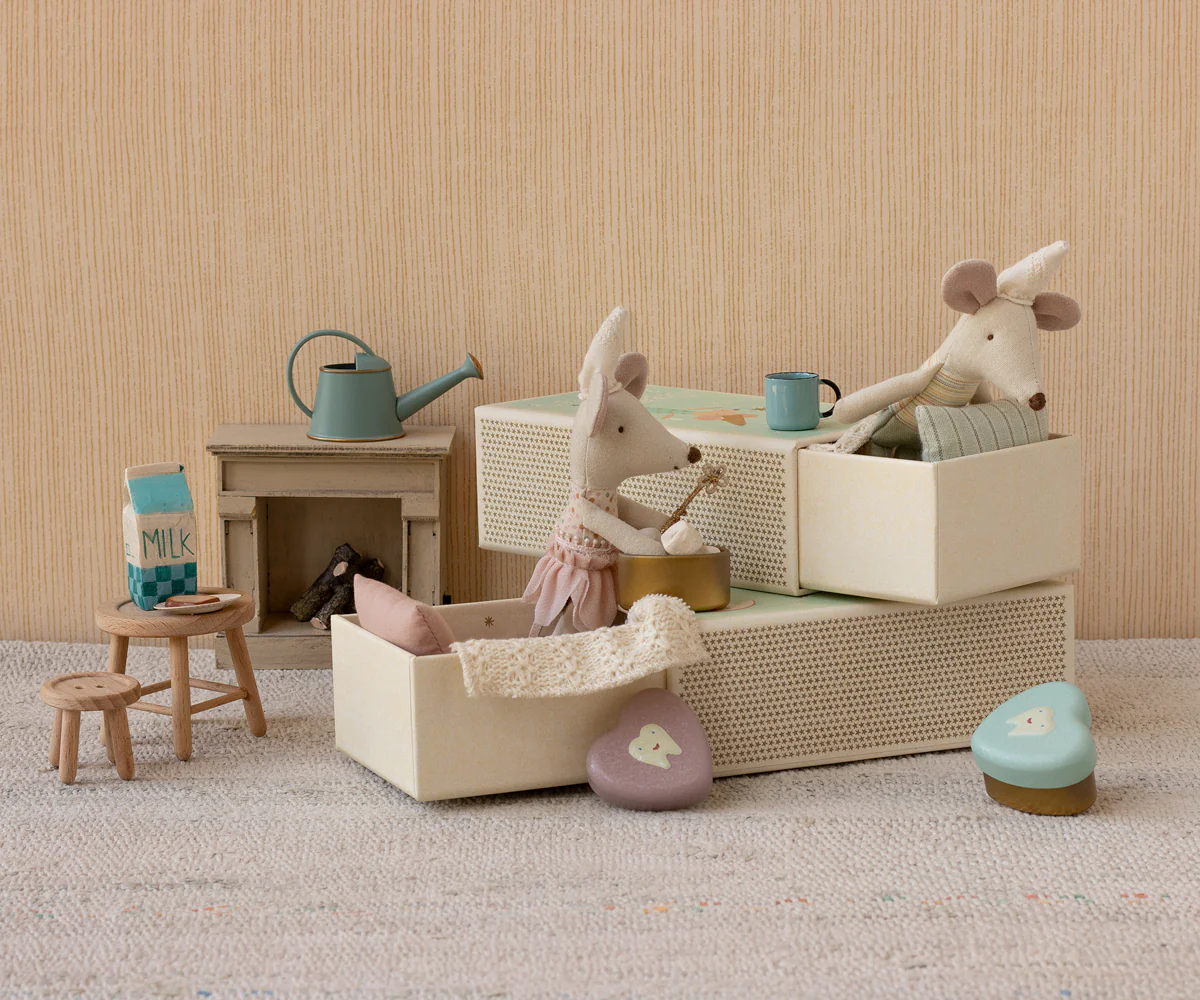 Wooden toy furniture and accessories arranged in a minimalist pastel scene with turquoise accents on beige carpet.