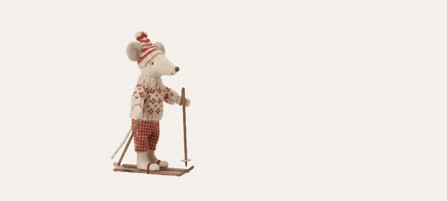 A charming felt mouse figurine dressed in a red Nordic sweater and hat, skiing with poles on a white background.