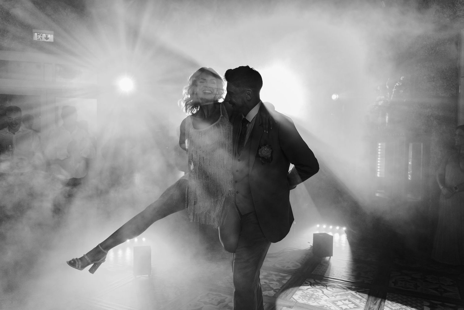 Silhouettes of performers moving through atmospheric fog and stage lighting during a concert performance.