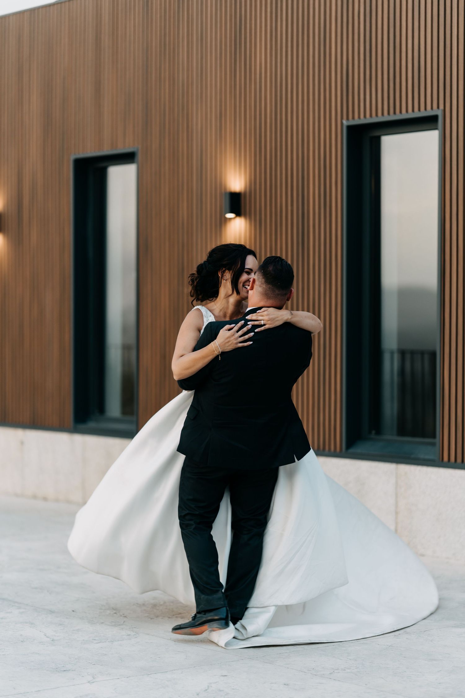 A romantic sequence of wedding photos showing a couple in black and white attire dancing and dipping against a modern wall.