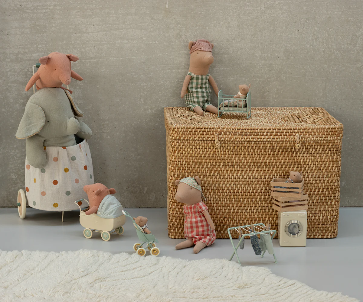 Plush toys and stuffed animals arranged in a row next to a woven wicker basket on a gray textured surface.