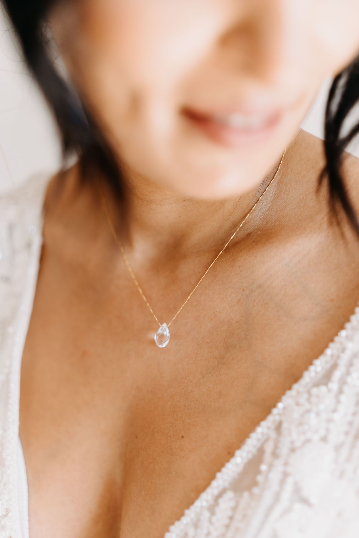 Close-up photo of a delicate crescent moon necklace on a silver chain against a white lace top.