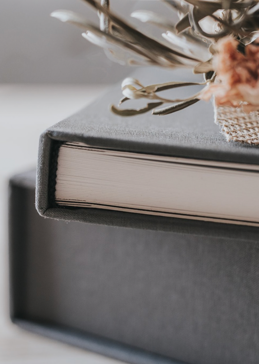 Close-up view of gray hardcover book with delicate flowers resting on top, creating a soft, dreamy aesthetic.