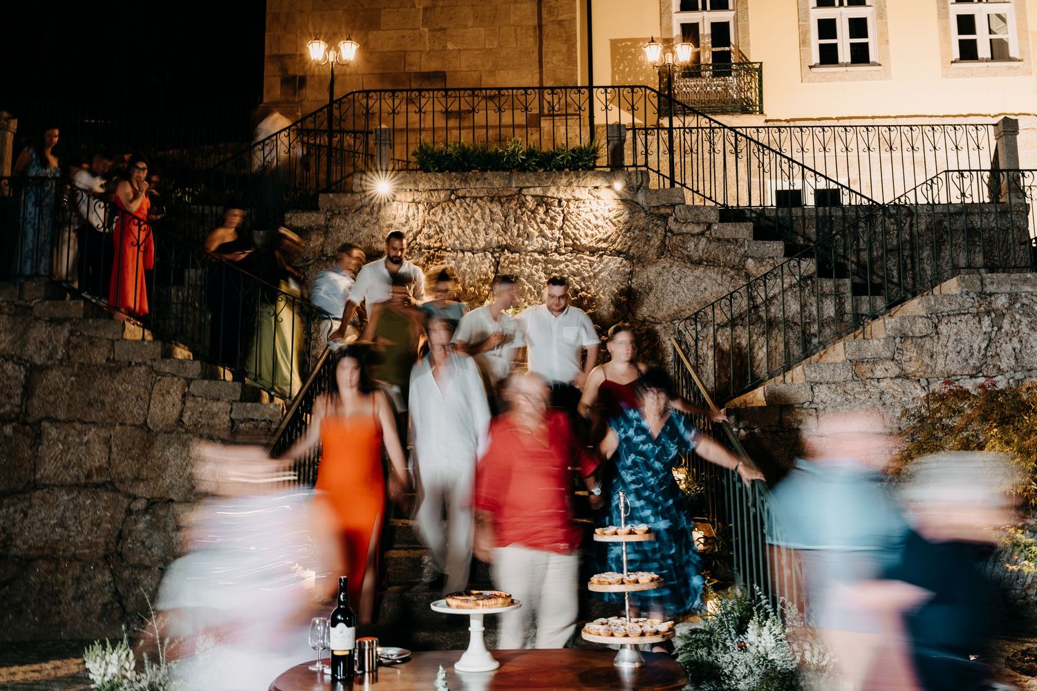 People dancing and socializing in a rustic indoor venue with stone walls lit by warm lighting.