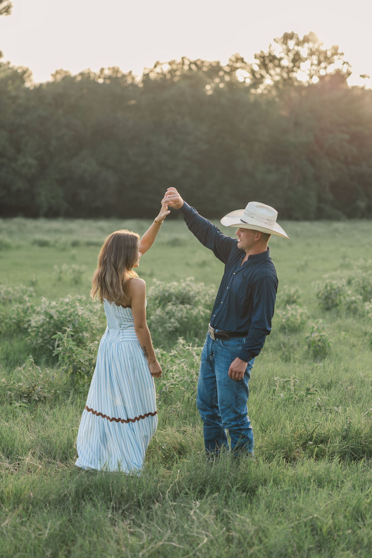 A couple poses for a photo in a field at golden hour during a Houston TX family photo shoot.
