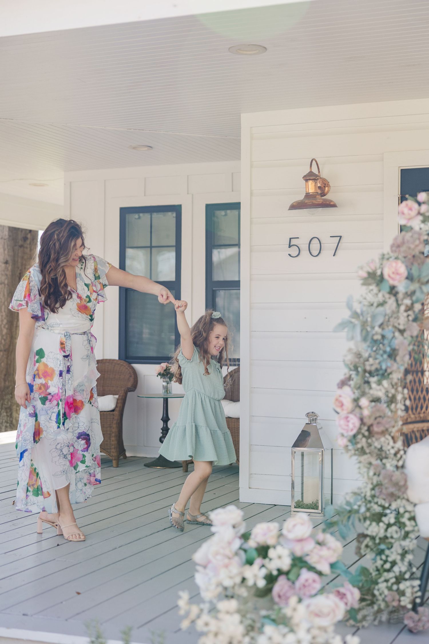 Woman in floral dress dancing with her young daughter during a photoshoot with a Houston family photographer.