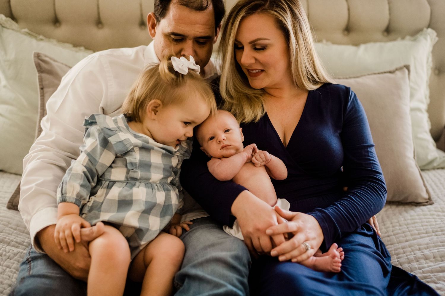 A family shares an intimate moment together on a tufted headboard bed.