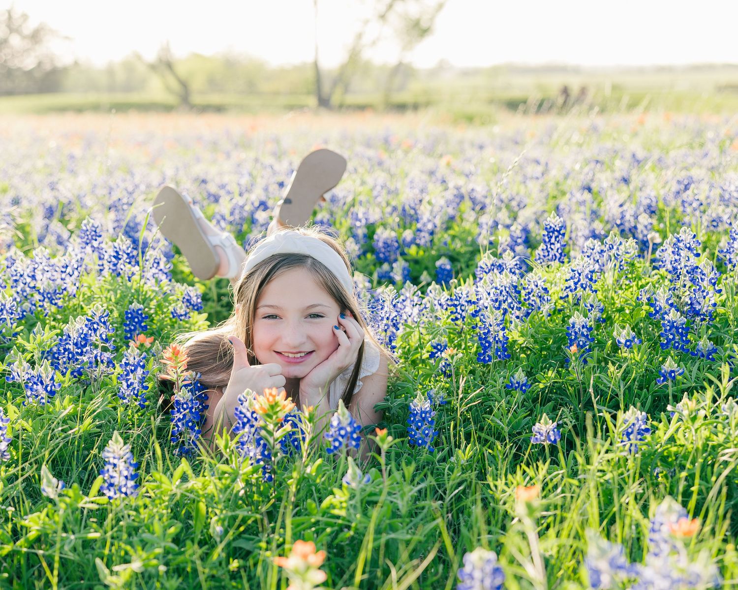 Person lying in field of bluebonnets wearing bunny ears in spring.