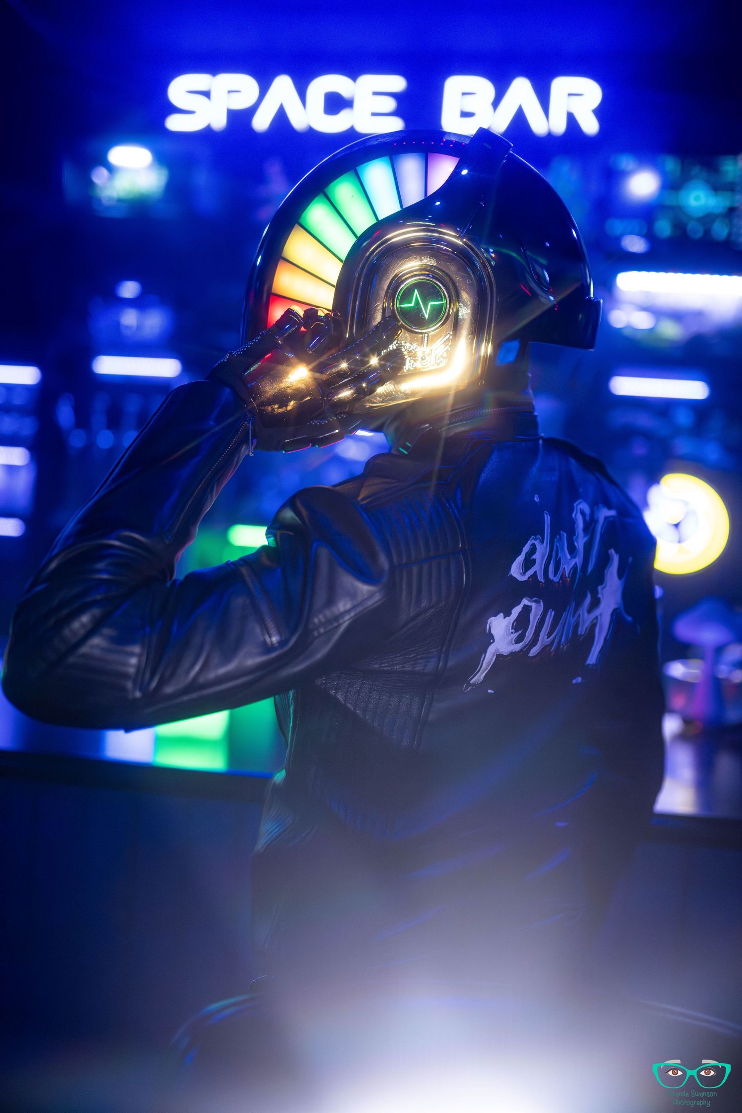 A figure in a futuristic helmet poses against a neon blue background with 'SPACE BAR' signage glowing above.